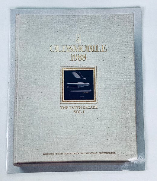 Cover of the 1988 Oldsmobile Tenth Decade Vol 1 Dealer Showroom Sales Brochure Guide Catalog, featuring elegant gold lettering and an image of an Oldsmobile vehicle. A vintage collectible item highlighting automotive history.