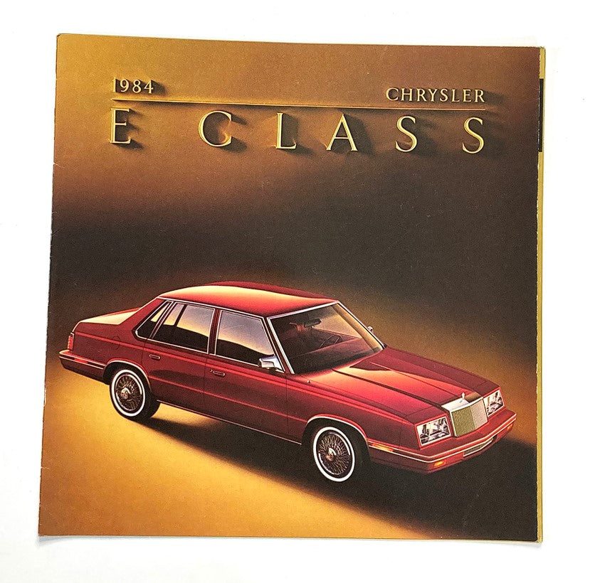 1984 Chrysler E Class Dealer Showroom Sales Brochure featuring a red Chrysler E Class car on a gold background, highlighting the vehicle's design and features.