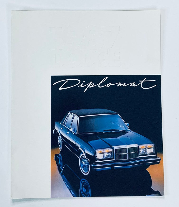 1987 Dodge Diplomat Dealer Showroom Sales Brochure Guide Catalog featuring a striking image of the Dodge Diplomat car in a showroom setting.
