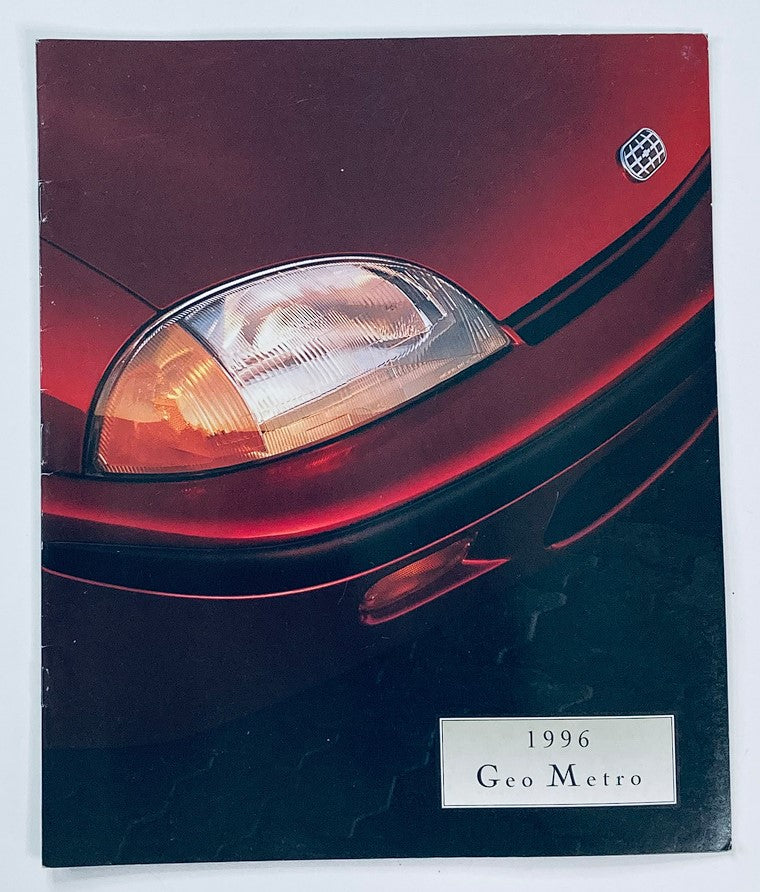 1996 GM Geo Metro Dealer Showroom Sales Brochure featuring a close-up of the car's headlight and front design, showcasing the sleek red color and stylish features of the Geo Metro model.