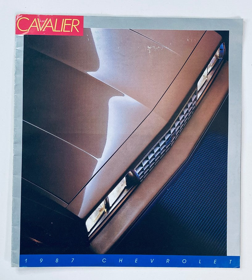 1987 Chevrolet Cavalier Dealer Showroom Sales Brochure Guide Catalog, featuring a close-up view of the car's front end showcasing its distinctive grille and headlights.