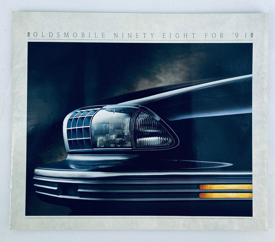 1991 Oldsmobile Ninety Eight Dealer Showroom Sales Brochure featuring a close-up image of the car's stylish headlight design, showcasing the vehicle's features and aesthetic appeal.