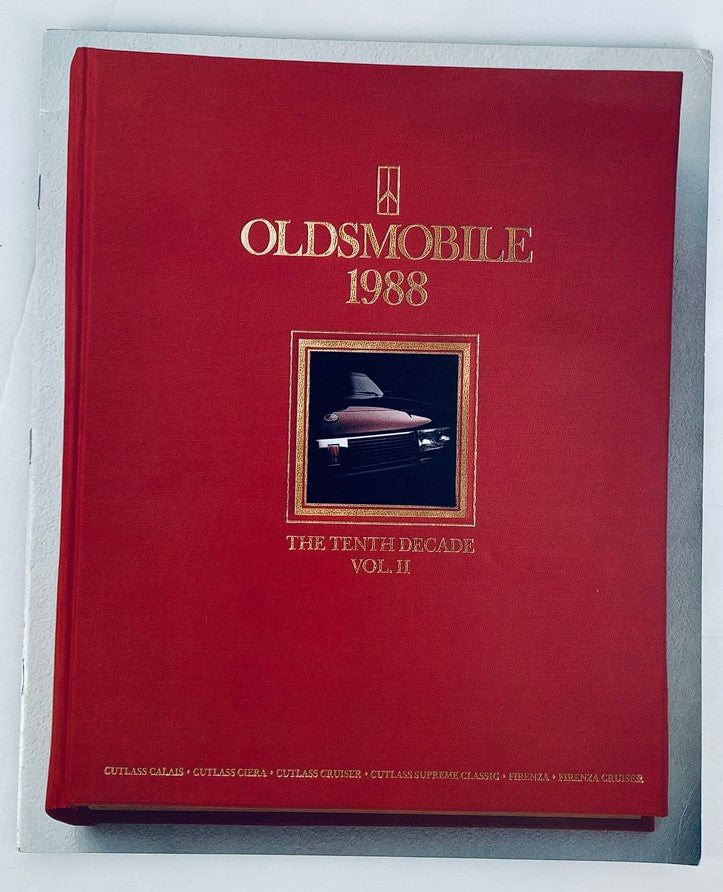 1988 Oldsmobile 10th Decade Vol II Dealer Showroom Sales Brochure Guide Catalog featuring a classic red cover with a gold emblem and an image of an Oldsmobile vehicle.