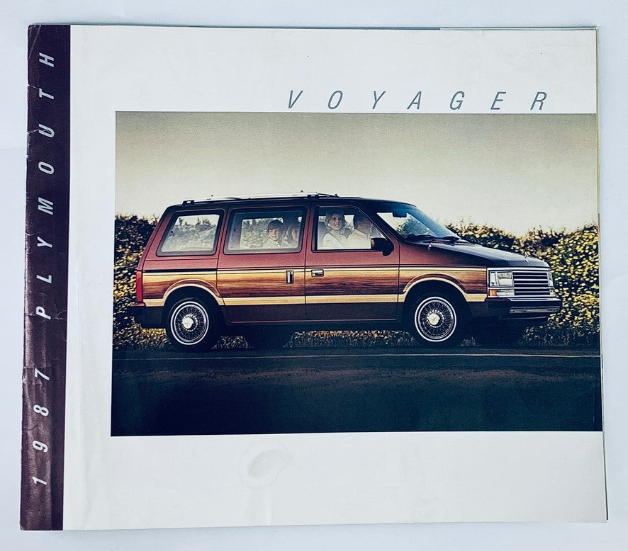 1987 Plymouth Voyager Dealer Showroom Sales Brochure showcasing the iconic minivan parked on the side of the road with passengers in the vehicle, emphasizing its innovative design and family-friendly features.
