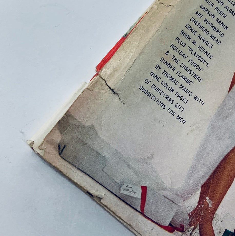 Close-up view of the side of VTG Playboy Magazine December 1962, highlighting the worn edges and vintage details, capturing its collectible significance.