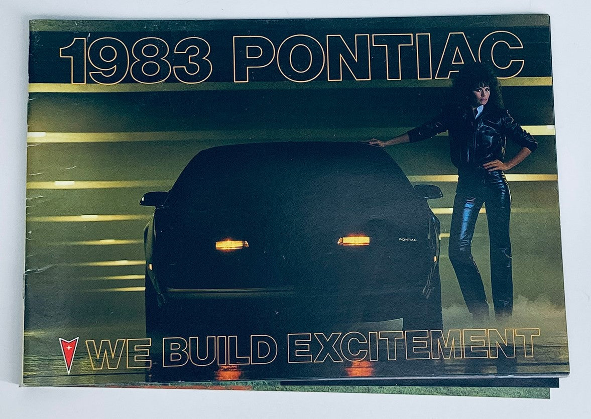 Cover of the 1983 Pontiac Full Lineup Dealer Showroom Sales Brochure featuring a silhouetted car and a model, emphasizing Pontiac's tagline 'We Build Excitement'.