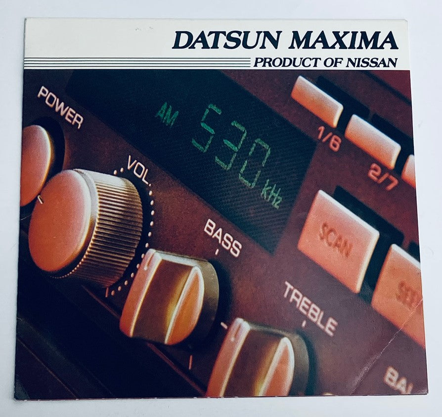 Close-up of a Datsun Maxima audio control panel featuring AM radio frequency dial, volume knob, and bass/treble settings, showcasing the vintage design of the 1982 Nissan Datsun Maxima Dealer Showroom Sales Brochure Guide Catalog.