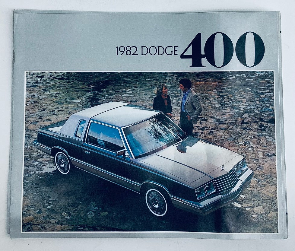 1982 Dodge 400 Dealer Showroom Sales Brochure Guide Catalog featuring a sleek gray Dodge 400 on a cobblestone driveway with two people discussing nearby.
