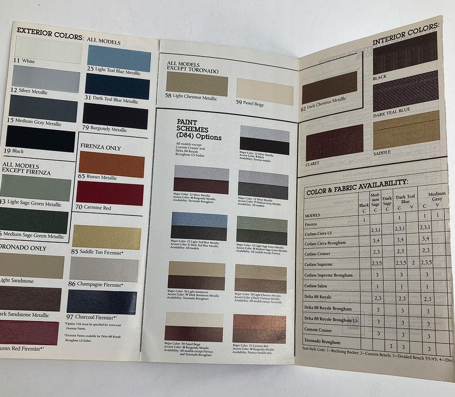 Close-up view of the 1986 Oldsmobile Information Network Dealer Showroom Sales Brochure displaying exterior colors, interior color choices, and fabric options for various models.