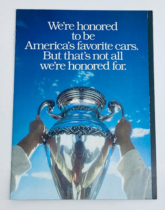 Cover of the 1990 Geo Full Lineup Dealer Showroom Sales Guide Catalog featuring an artistic image of a silver trophy held against a blue sky with the text 'We're honored to be America's favorite cars. But that's not all we're honored for.'