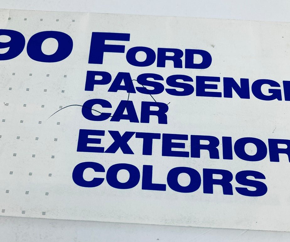 Close-up of the 1990 Ford Passenger Car Exterior Colors Dealer Showroom Sales Brochure Catalog displaying details of the cover with visible marks and creases.