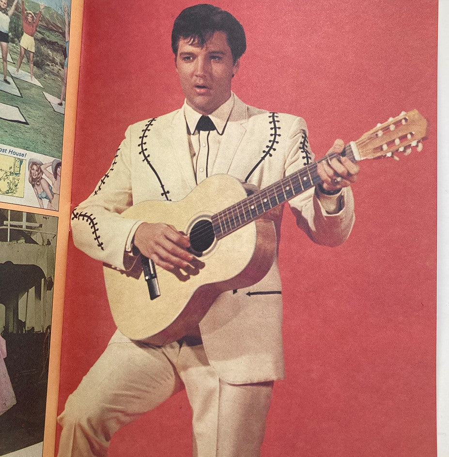 Elvis Presley performing with a guitar in a white suit, captured in an interior image from the VTG Photoplay Presents Magazine 1982 Elvis Presley Memorial.