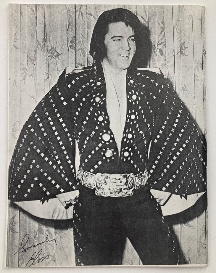 VTG 1981 Remember Elvis Presley by D.J. Fontana: Elvis Presley smiling and striking a pose in a stylish outfit adorned with rhinestones, reflecting his flashy performance style.