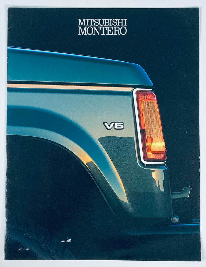 1990 Mitsubishi Montero Dealer Showroom Sales Brochure Cover featuring a close-up of the V6 badge and taillight, showcasing the vehicle's design and branding.