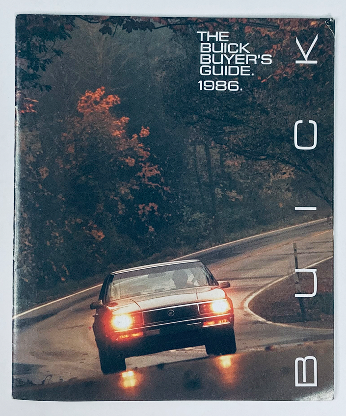 1986 Buick Dealer Showroom Sales Brochure Guide Catalog featuring a Buick vehicle on a scenic road with fall foliage, showcasing the 1986 model lineup and features.