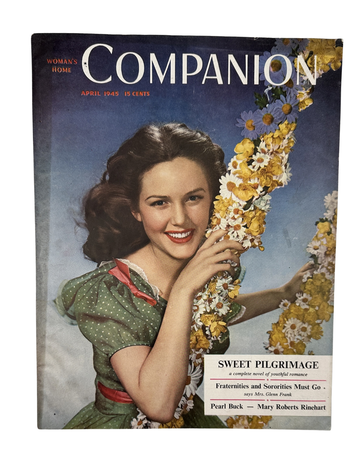 Cover of Woman’s Home Companion Magazine April 1945 featuring the title 'Sweet Pilgrimage'. The cover showcases a woman smiling while holding a bouquet of flowers, symbolizing themes of love and beauty. This vintage magazine features contributions from Pearl Buck and other notable authors.