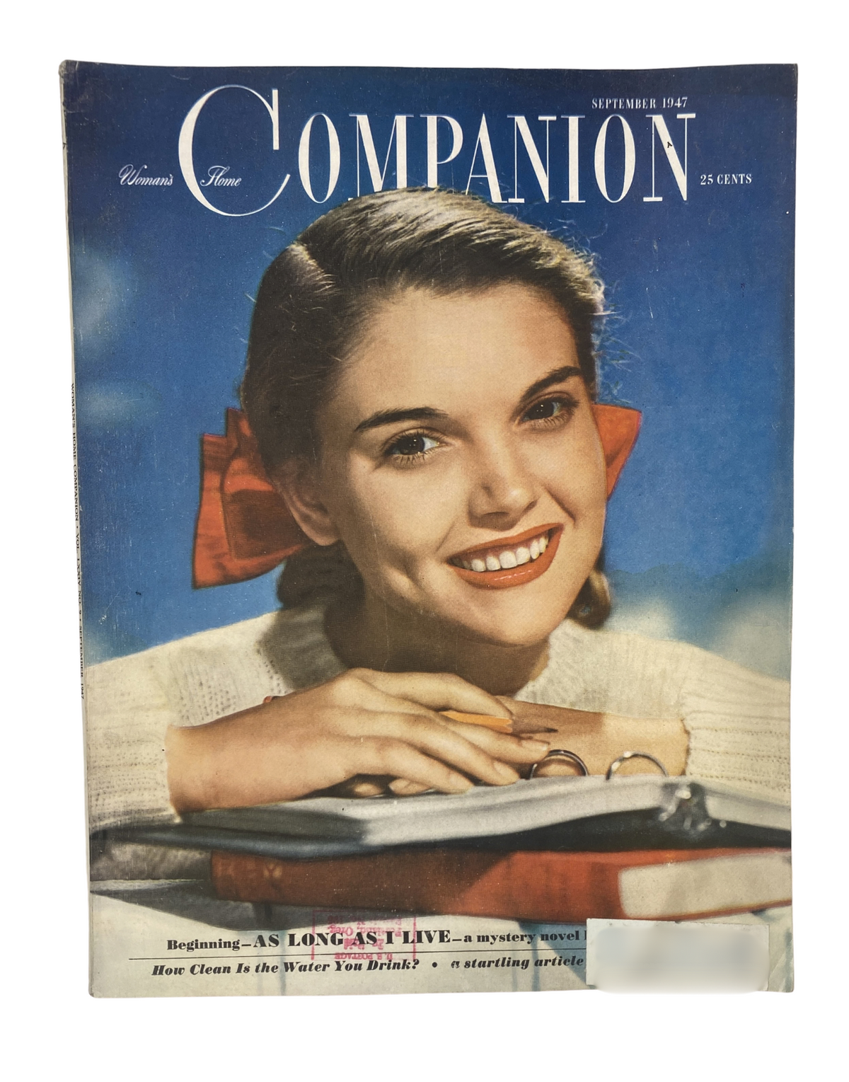 Cover of Woman’s Home Companion Magazine from September 1947 featuring a smiling woman with a bow in her hair. The magazine title is prominently displayed, along with the subtitle 'As Long As I Live - a mystery novel.' This vintage magazine cover showcases mid-20th century fashion and design.