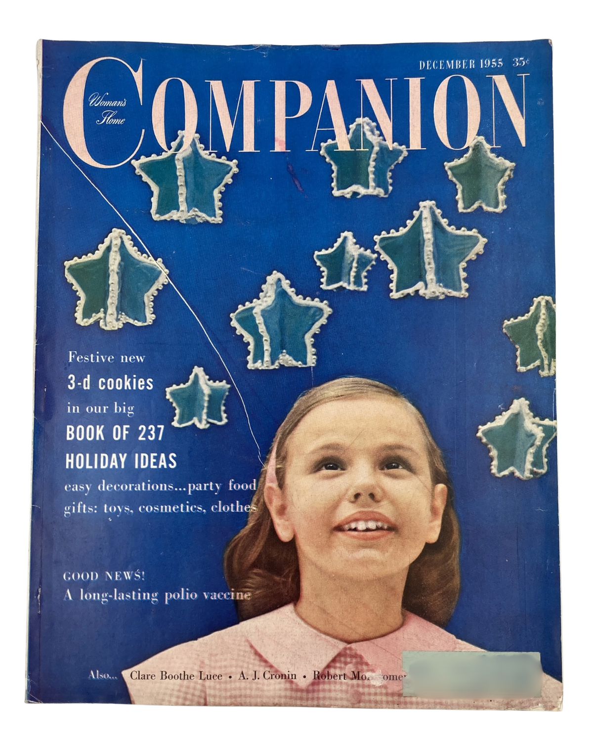 Cover of Woman’s Home Companion Magazine December 1955 featuring festive 3-d cookies, holiday ideas, and a smiling young girl with decorations of snowflakes. Complete with articles on party food, toys, and cosmetics.