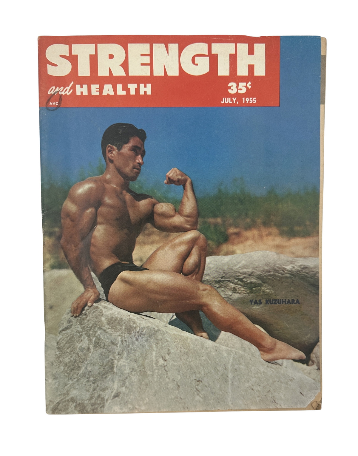 Cover of Strength and Health Magazine July 1955 featuring Yas Kuzuhara showcasing a muscular pose near large rocks, highlighting the publication's focus on weightlifting and fitness.